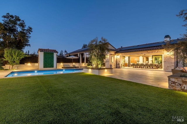 exterior space with an outdoor pool, solar panels, a patio, a lawn, and a fenced backyard