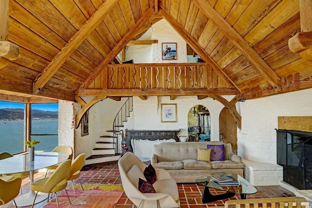 living room featuring wood ceiling, beam ceiling, high vaulted ceiling, a water view, and a brick fireplace