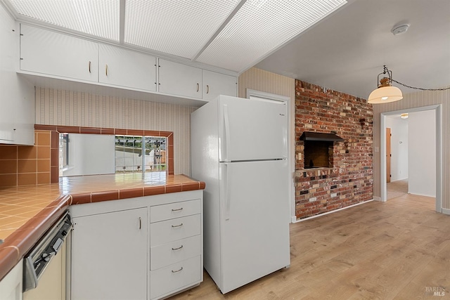 kitchen featuring hanging light fixtures, white refrigerator, tile counters, light hardwood / wood-style floors, and white cabinets