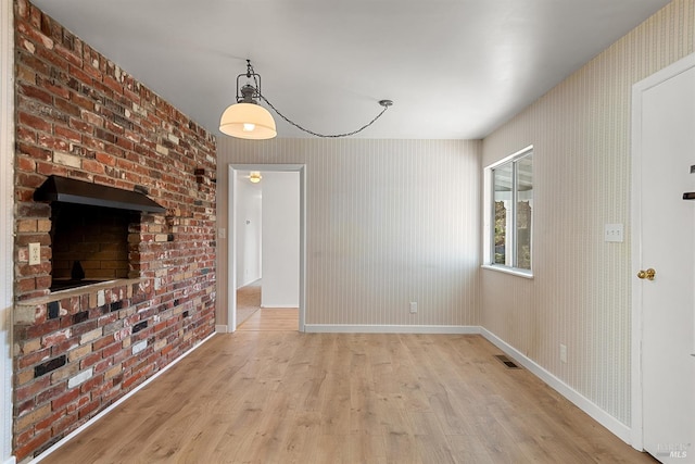 unfurnished living room featuring a fireplace and light hardwood / wood-style floors