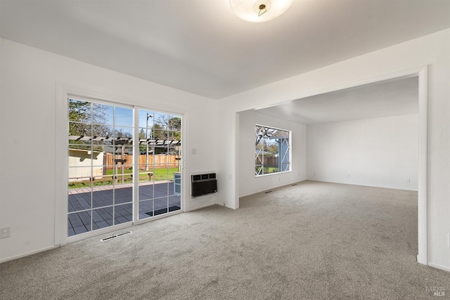 unfurnished living room with plenty of natural light, carpet floors, and heating unit