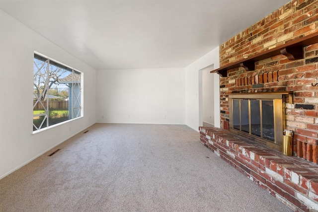 unfurnished living room with carpet flooring and a brick fireplace