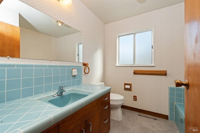 bathroom with vanity, a washtub, tile patterned floors, and toilet