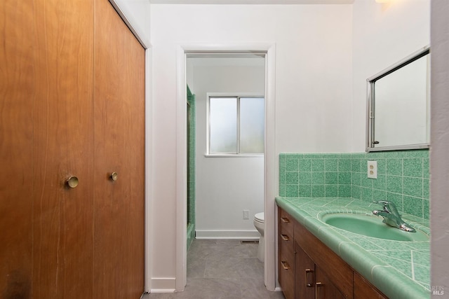 bathroom with tasteful backsplash, vanity, tile patterned floors, and toilet