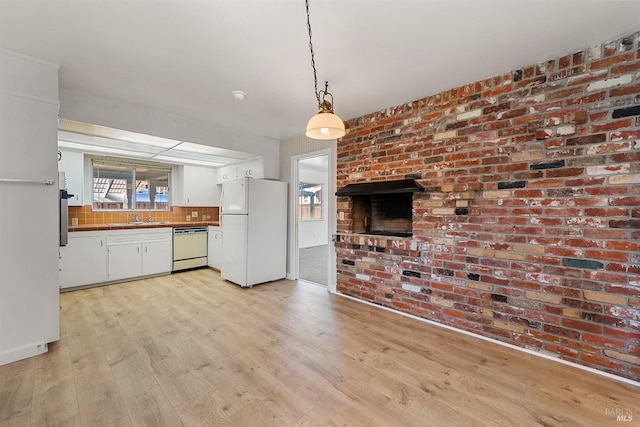 kitchen with pendant lighting, sink, white cabinets, white appliances, and light wood-type flooring