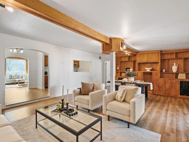 living room with beamed ceiling and light wood-type flooring