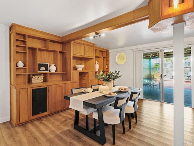 dining area with beam ceiling, light hardwood / wood-style floors, and ornate columns