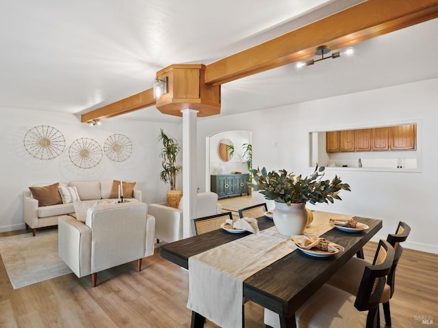 dining area with beam ceiling, light hardwood / wood-style floors, and decorative columns