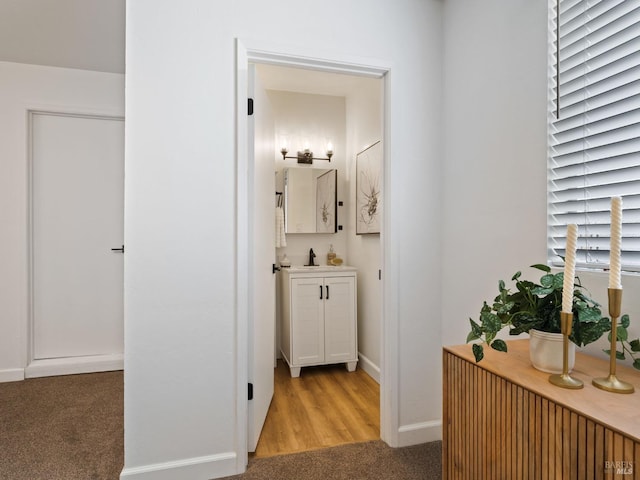 corridor featuring sink and carpet flooring