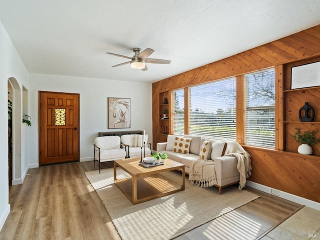 living room featuring wooden walls, light hardwood / wood-style floors, and ceiling fan