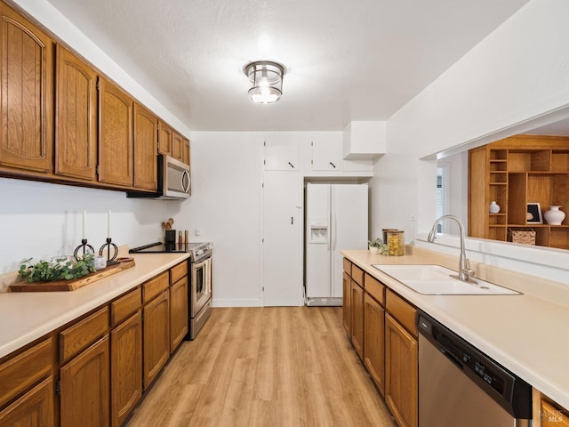 kitchen featuring appliances with stainless steel finishes, sink, and light wood-type flooring