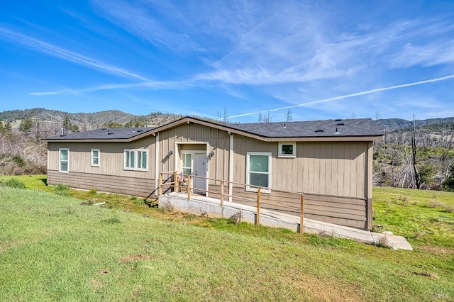 rear view of house featuring a mountain view and a yard