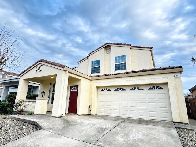 view of front of house with driveway, fence, a tile roof, and stucco siding