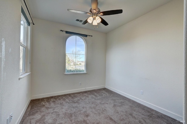 carpeted spare room with ceiling fan and plenty of natural light