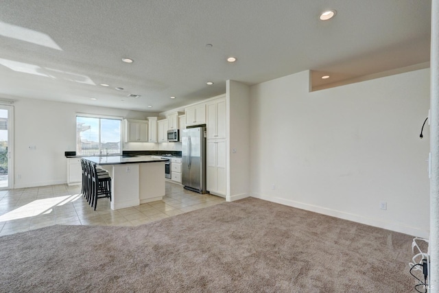 kitchen with a breakfast bar, white cabinetry, a kitchen island, light colored carpet, and stainless steel appliances