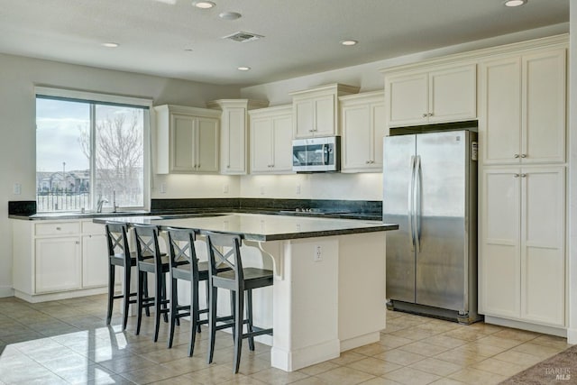 kitchen with appliances with stainless steel finishes, a breakfast bar area, a kitchen island, and light tile patterned floors