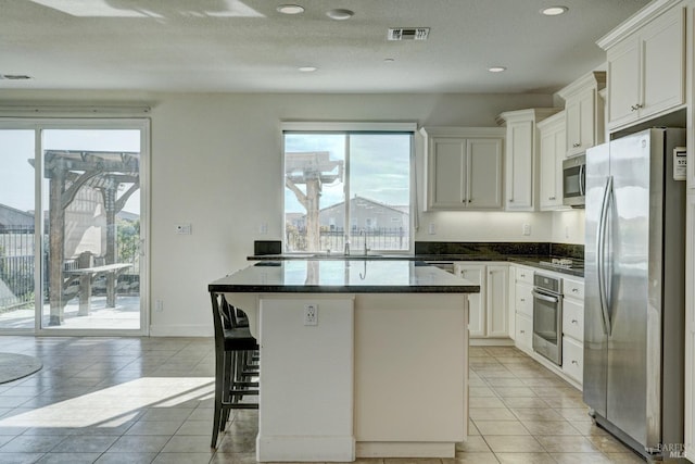 kitchen with white cabinetry, light tile patterned floors, stainless steel appliances, and a kitchen breakfast bar