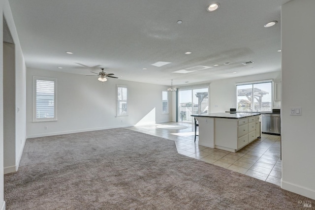 kitchen featuring dishwasher, white cabinets, hanging light fixtures, a center island, and light carpet