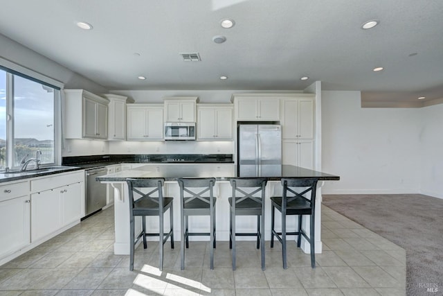 kitchen with appliances with stainless steel finishes, a center island, sink, and a breakfast bar area