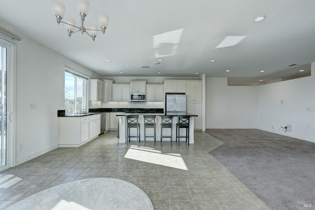 kitchen with a breakfast bar, white cabinetry, stainless steel appliances, a center island, and light tile patterned flooring