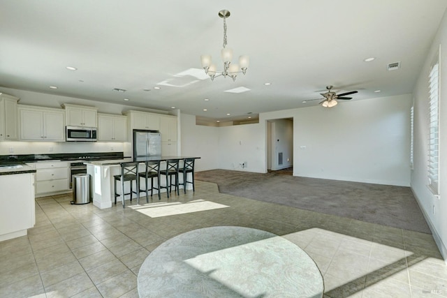 kitchen featuring a breakfast bar, white cabinetry, hanging light fixtures, light carpet, and appliances with stainless steel finishes