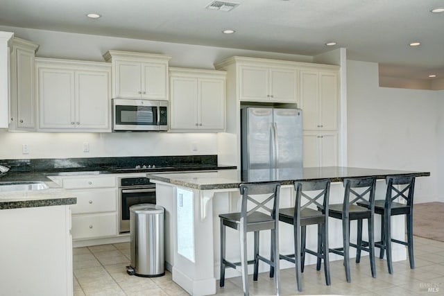 kitchen featuring dark stone countertops, a kitchen island, a kitchen breakfast bar, and appliances with stainless steel finishes