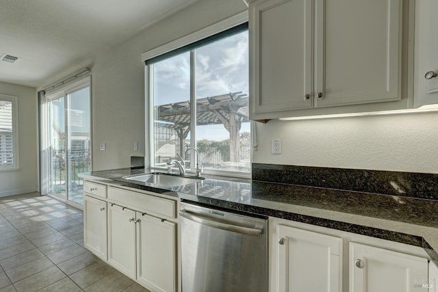 kitchen with light tile patterned floors, sink, dishwasher, dark stone countertops, and white cabinets