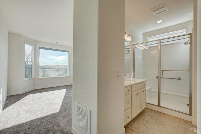 bathroom with walk in shower, vanity, and tile patterned flooring