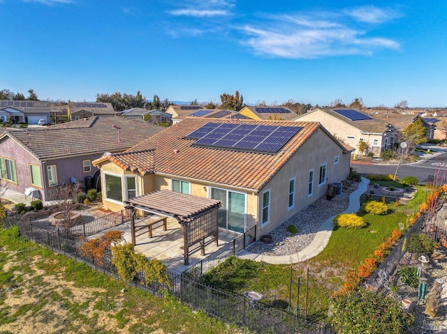 rear view of property featuring a pergola, a patio area, and solar panels