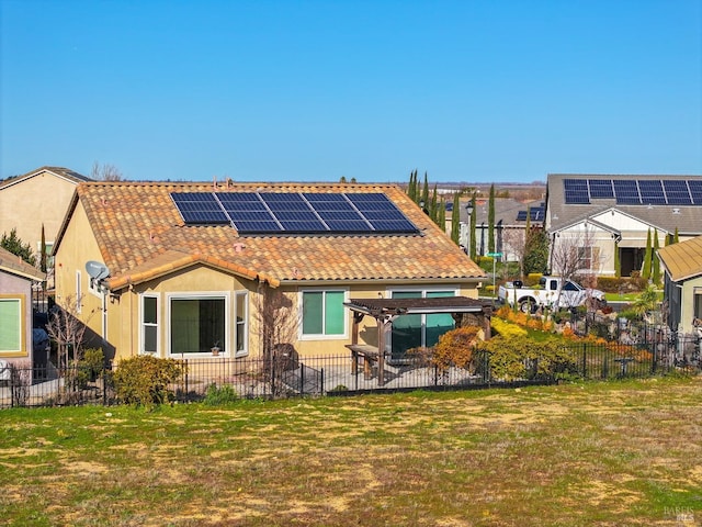 rear view of house featuring a lawn and solar panels