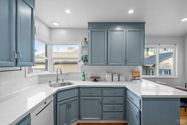 kitchen with sink, backsplash, white dishwasher, kitchen peninsula, and plenty of natural light