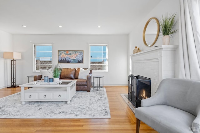 living room with a brick fireplace, plenty of natural light, and light wood-type flooring