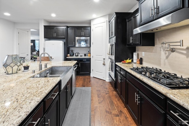 kitchen with dark hardwood / wood-style floors, stainless steel microwave, sink, white fridge, and gas cooktop