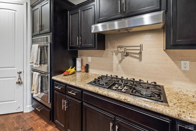 kitchen with stainless steel appliances, light stone counters, and decorative backsplash