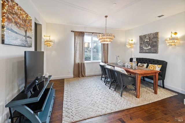 dining area with dark wood-type flooring and an inviting chandelier