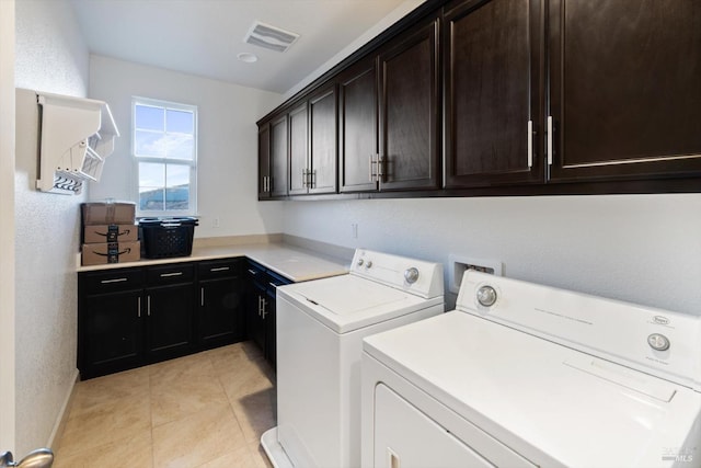 washroom with cabinets, washing machine and dryer, and light tile patterned flooring