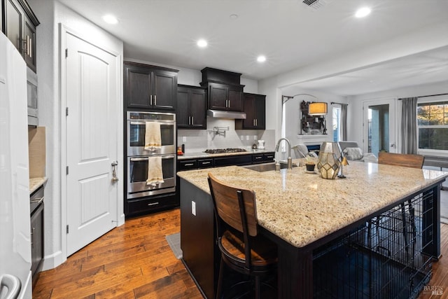 kitchen with sink, a breakfast bar area, appliances with stainless steel finishes, and a center island with sink