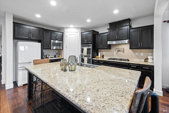 kitchen featuring appliances with stainless steel finishes, a kitchen bar, sink, and light stone counters