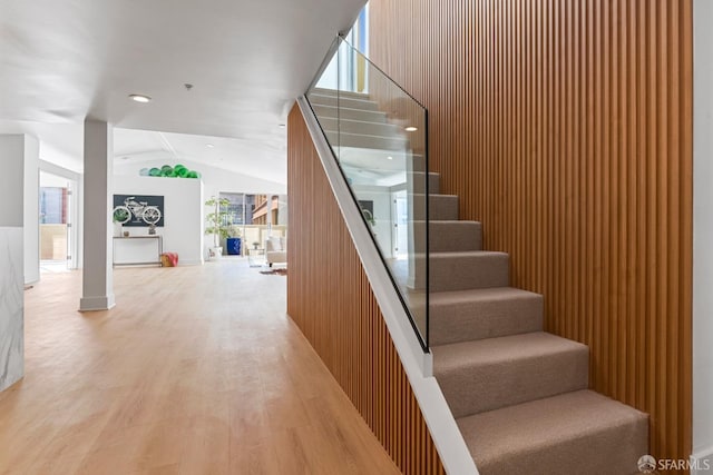 stairway with recessed lighting, lofted ceiling, and wood finished floors