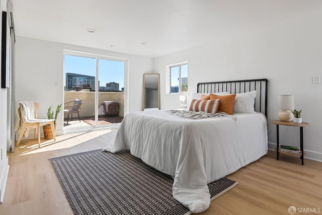 bedroom featuring baseboards, light wood-style floors, and access to exterior