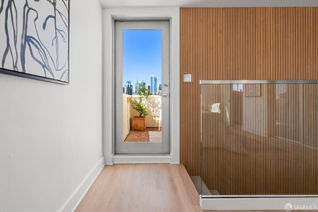 doorway to outside with baseboards, wood finished floors, and a city view