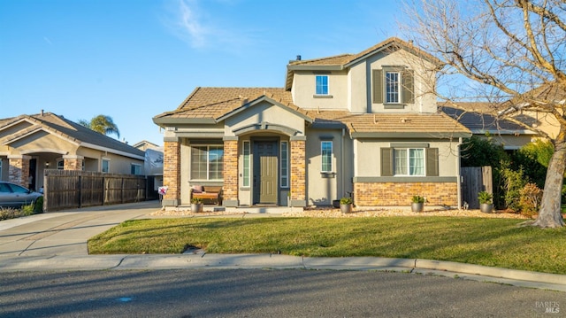 view of front of property with brick siding, fence, a tiled roof, stucco siding, and a front yard