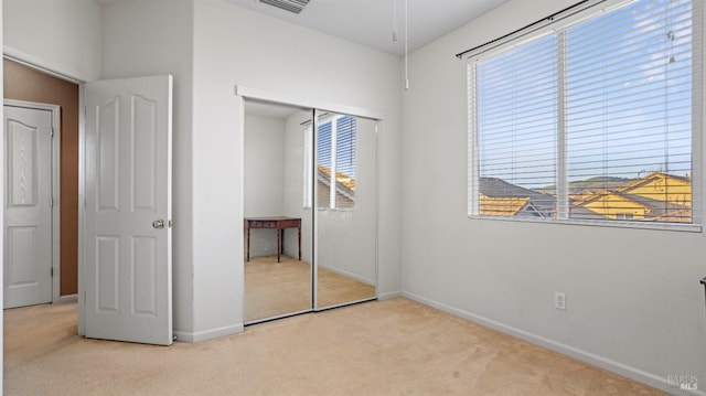 unfurnished bedroom featuring multiple windows, light colored carpet, and a closet