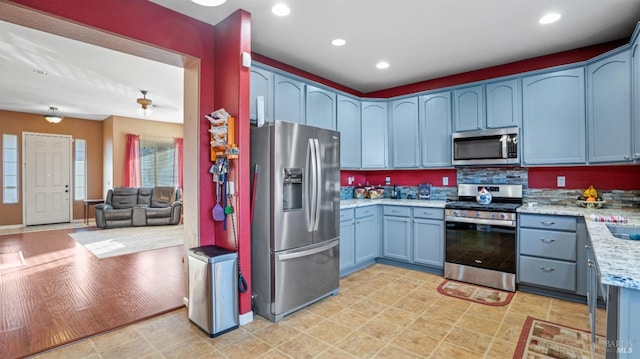 kitchen featuring stainless steel appliances and light stone counters