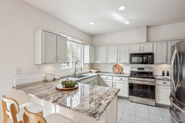 kitchen featuring appliances with stainless steel finishes, sink, white cabinets, light stone counters, and kitchen peninsula