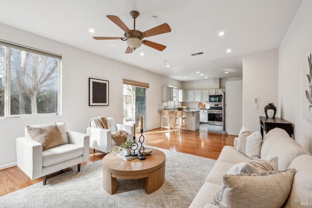 living room featuring ceiling fan and light hardwood / wood-style flooring