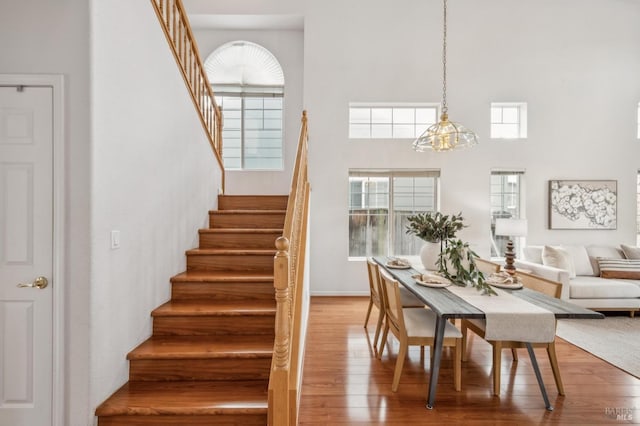 dining space with a towering ceiling and wood-type flooring