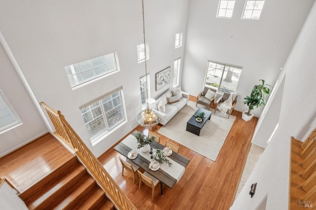 living room with a towering ceiling, a healthy amount of sunlight, and wood-type flooring