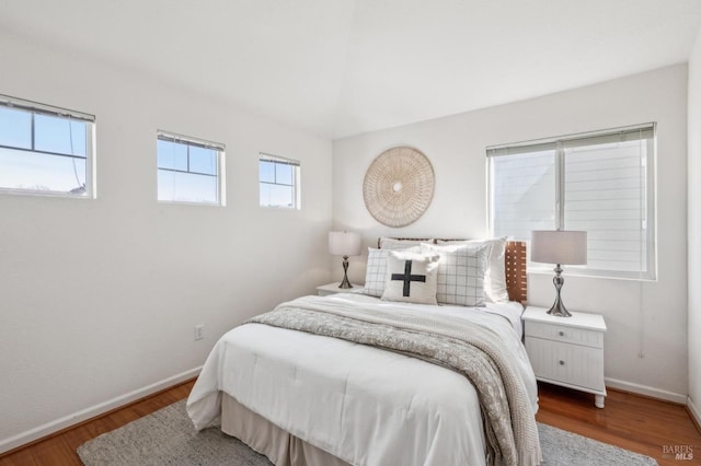 bedroom with multiple windows, hardwood / wood-style flooring, and lofted ceiling