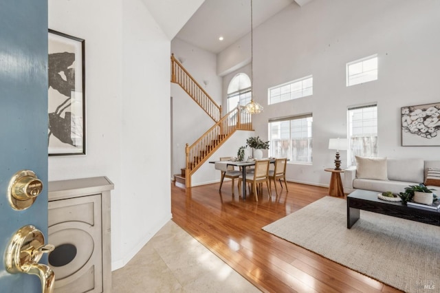 living room featuring a towering ceiling, a chandelier, and light wood-type flooring